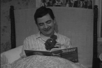 憨豆先生坐在床上拿着玩具看书gif图片
