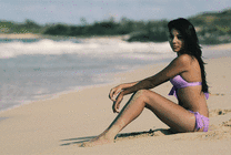 美女穿着比基尼坐在沙滩上拍写真GIF动态图