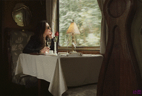 戴墨镜的女孩坐在窗边喝着鸡尾酒看向窗外gif图片