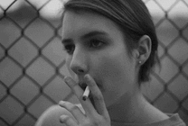 女人挽着头发站在围栏边大口的抽烟GIF图片