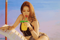 美丽的姑娘在海边的躺椅上喝果汁gif图片